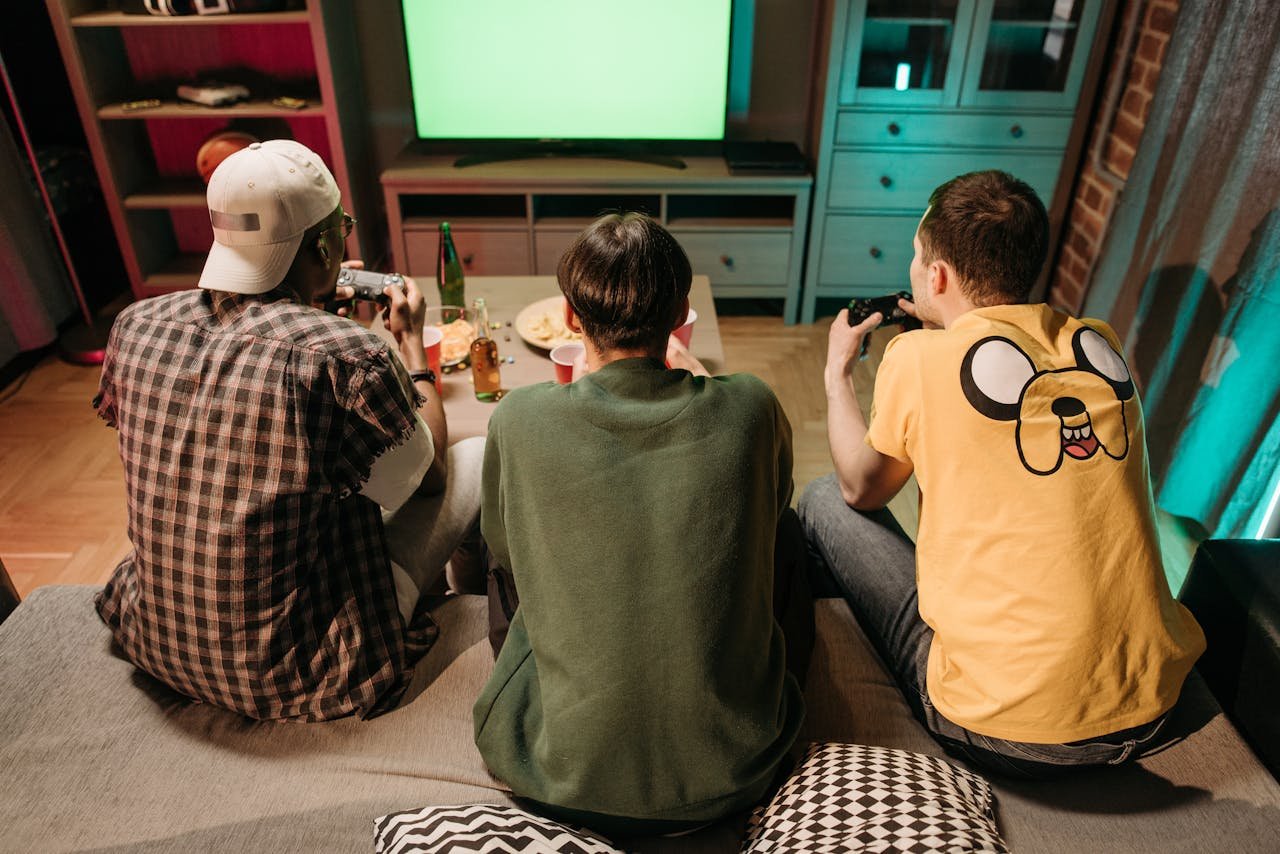 Three young men enjoying a home gaming session together, playing video games in a cozy indoors setting.